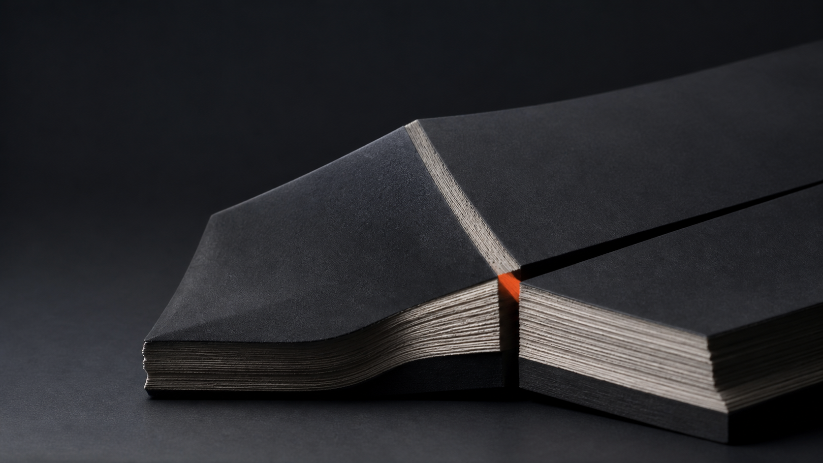 A dark layered surface cut at one orange decision seam